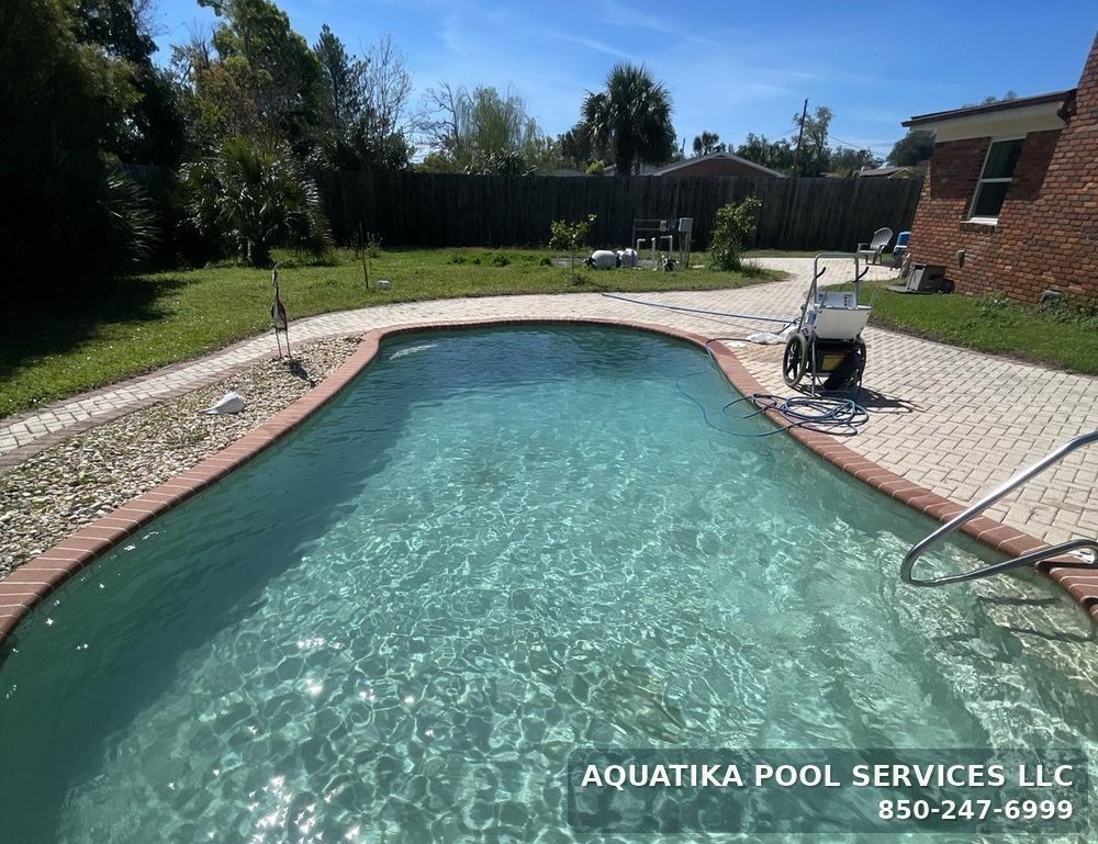 Kidney-shaped inground pool with brick coping cleaned by Aquatika Pool Services in Panama City