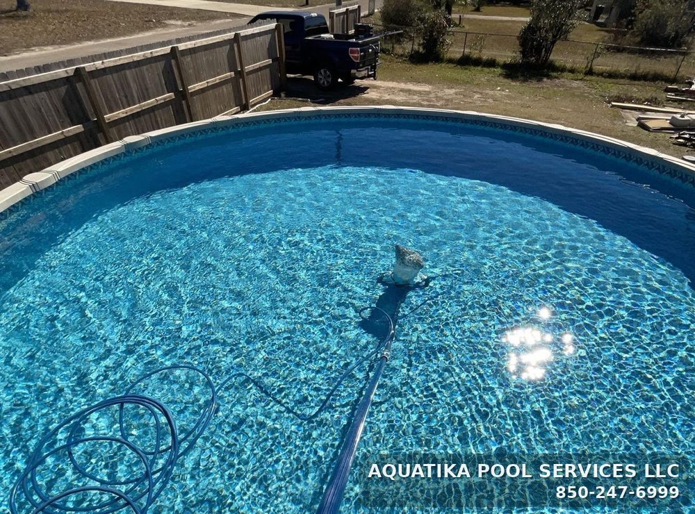 Vacuuming an above-ground pool in Panama City with the Aquatika service truck parked behind